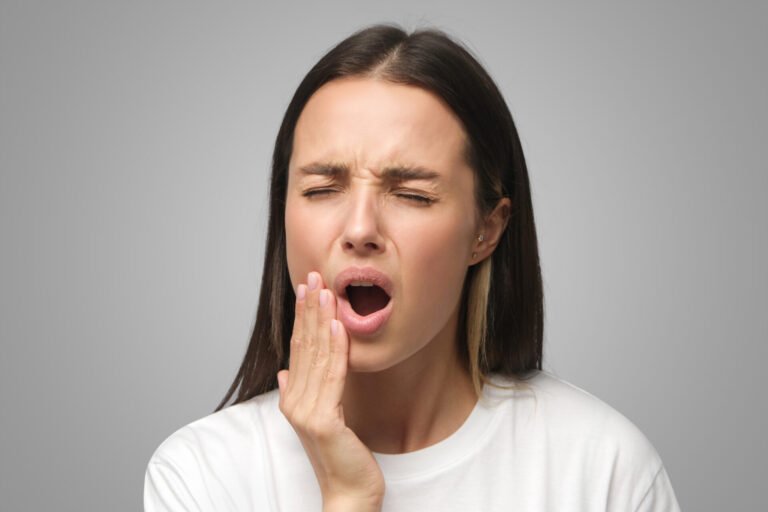 Young Woman Feeling Pain, Holding Cheek With Hand, Suffering From Bad Toothache, Isolated On Gray Emergency Dental image